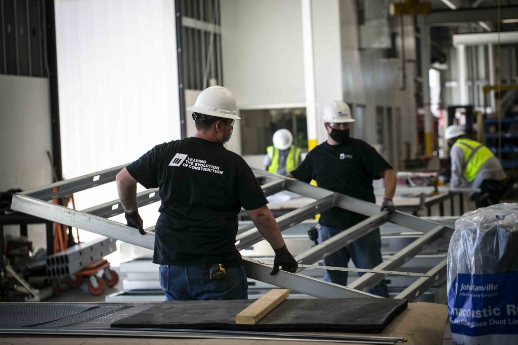 Wall panels during production in M3's manufacturing facility. Two employees work together to move an m-wall to a new station.